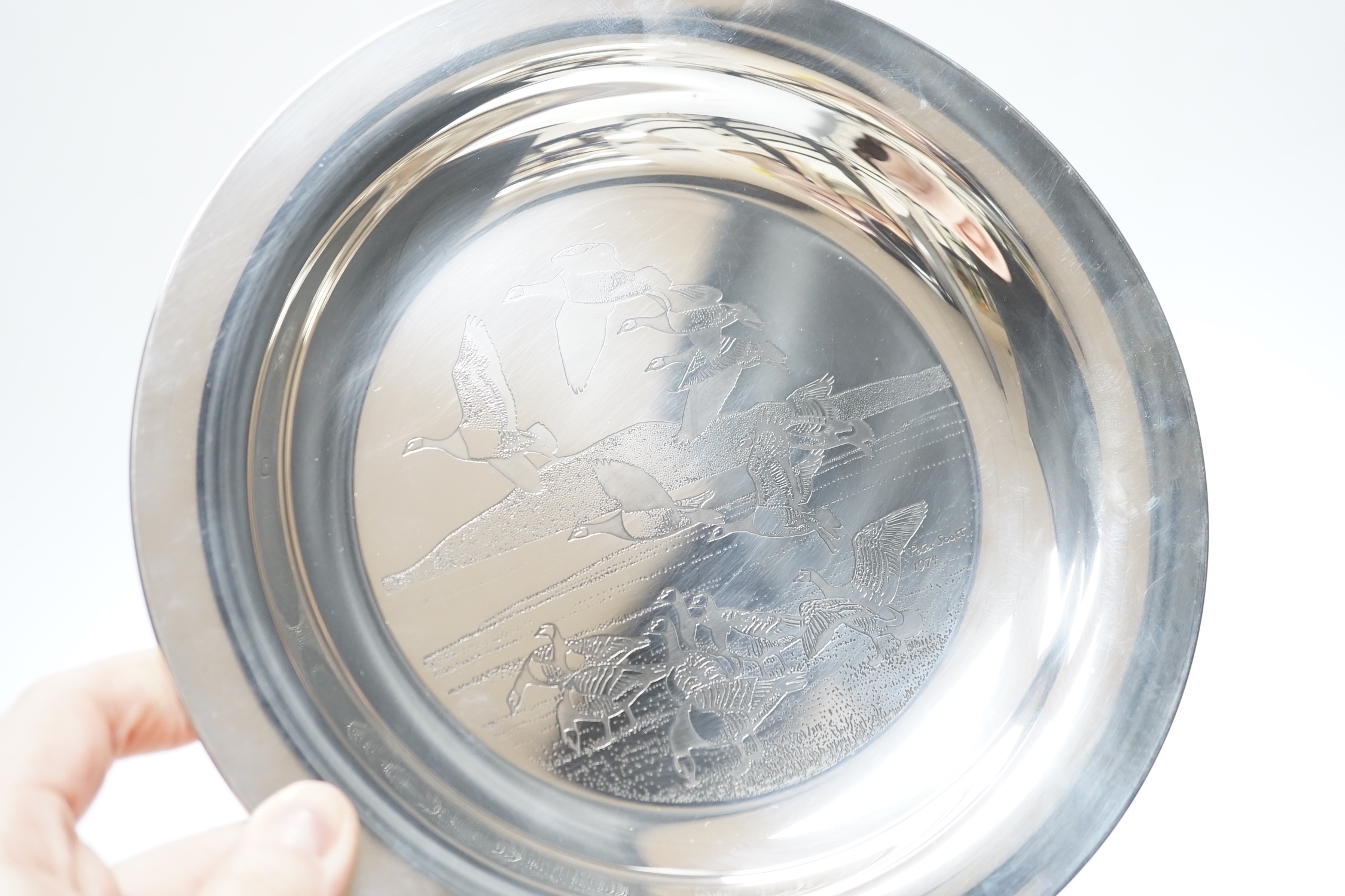 A boxed silver Peter Scott Christmas plate, 1974, depicting etched birds in flight, John Pinches, London 1974. Diameter 20.5cm, 5.9oz.
